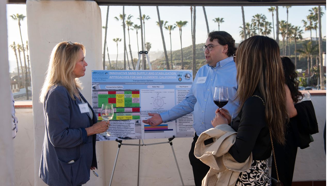 UCI grad student Jacob Samson (right) presents his solution to attendees of the Resilient Shores reception in San Clemente. (Steve Zylius/UCI)