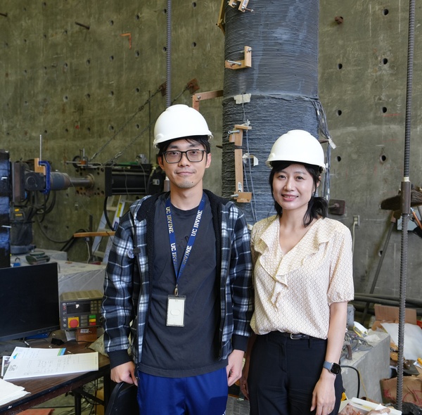 Professor Mo Li (right) poses next to a student, both wearing white construction hats.